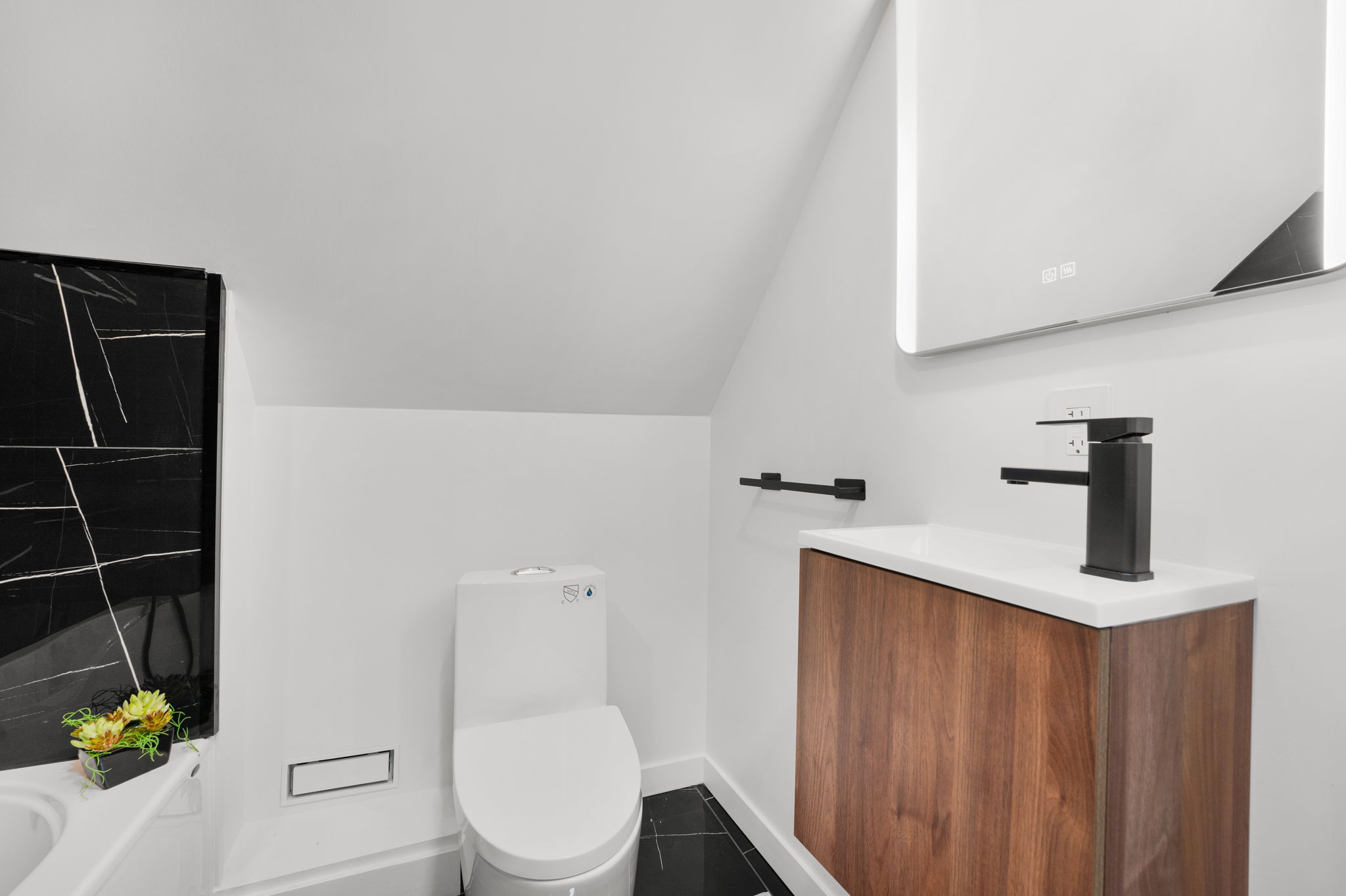 Modern powder room with black stone and a wood vanity