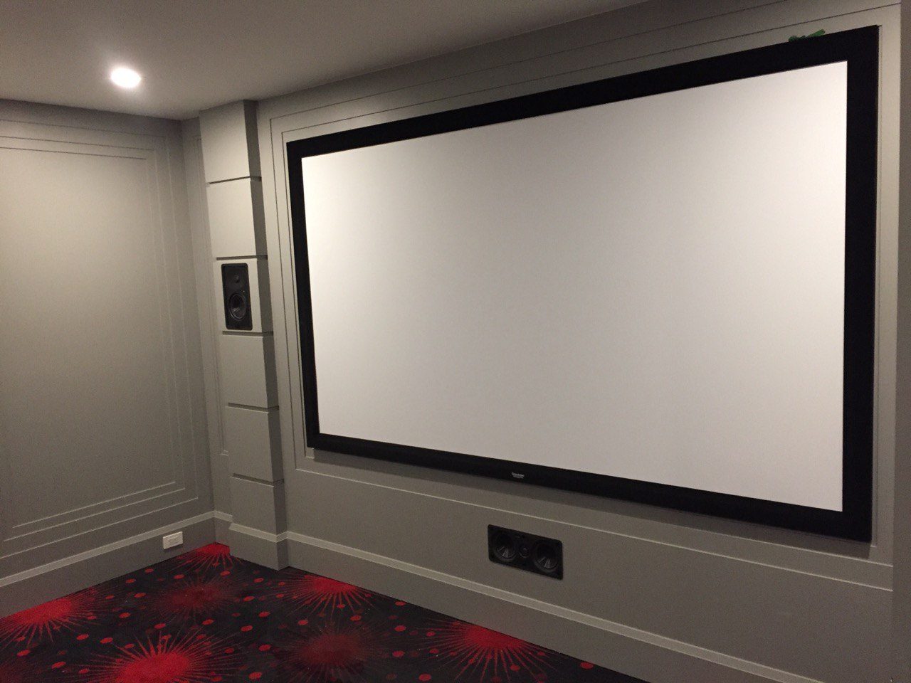 Dark home theatre with wall panelling and a large screen