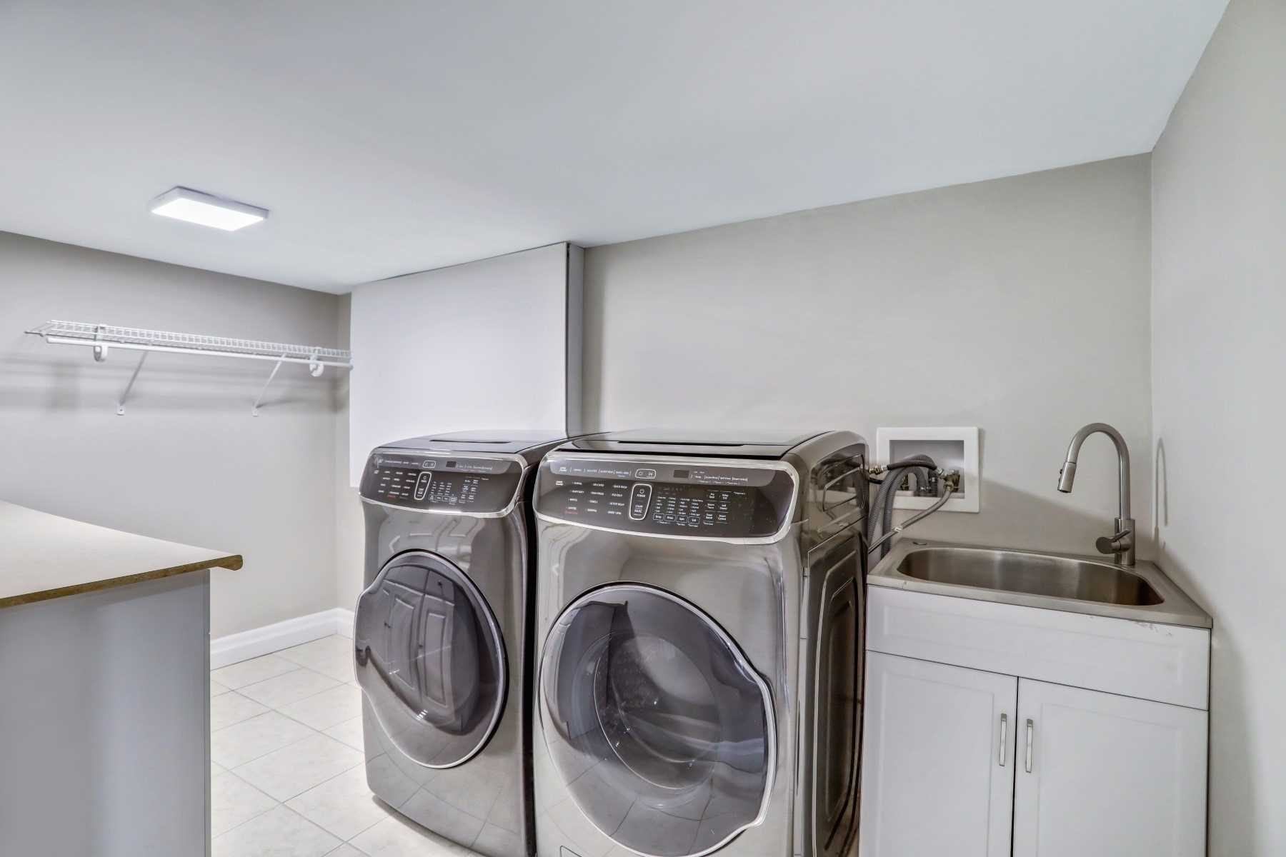 Finished basement laundry area with cabinetry and sink