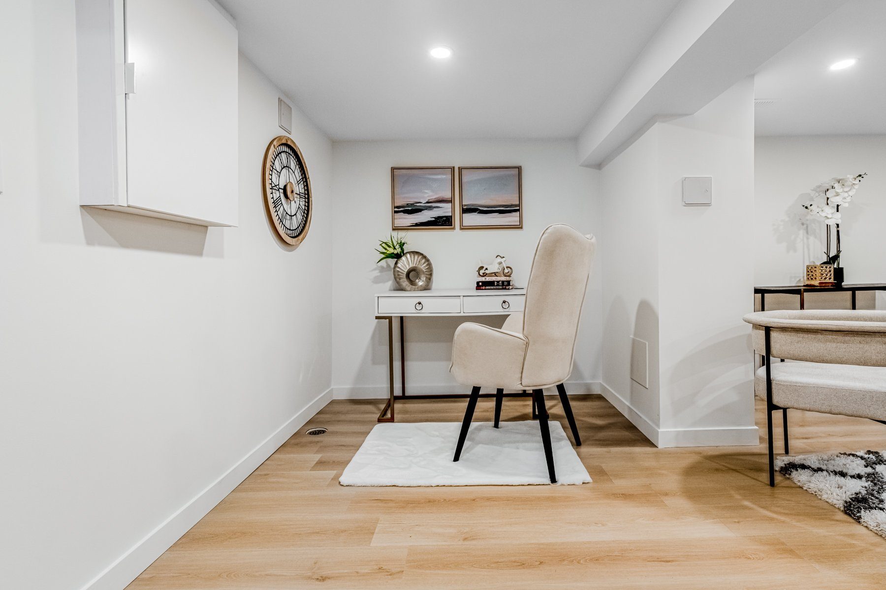 Staged basement dining and lounge space with light wood floors