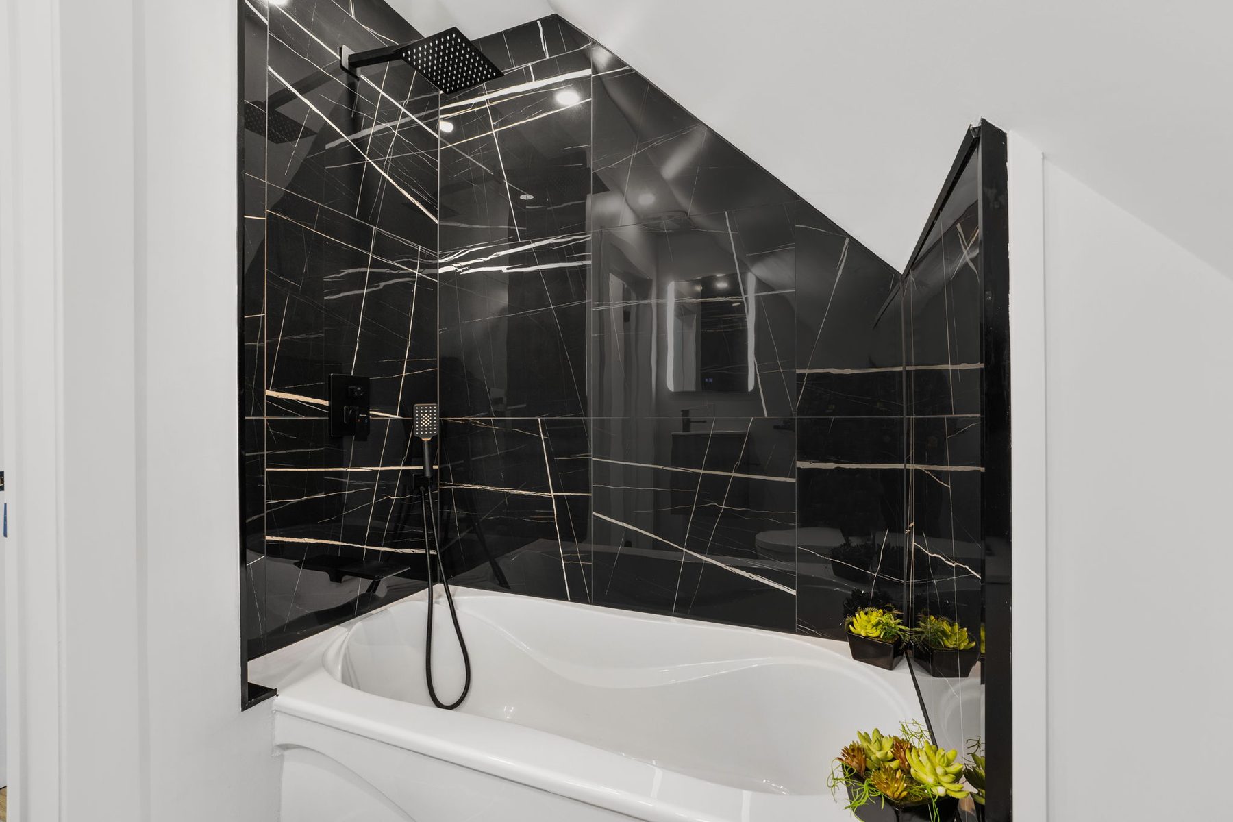 Black marble shower with frameless glass and matte black fittings