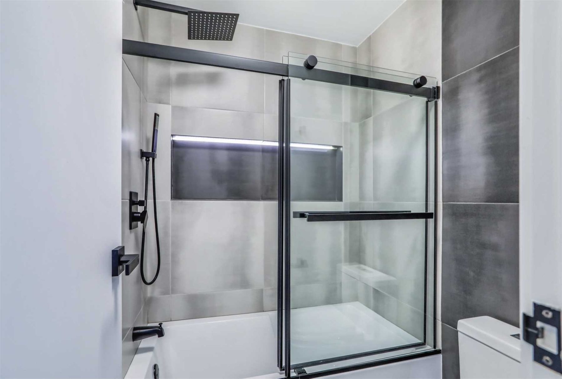 Grey tiled shower with black-framed sliding glass doors