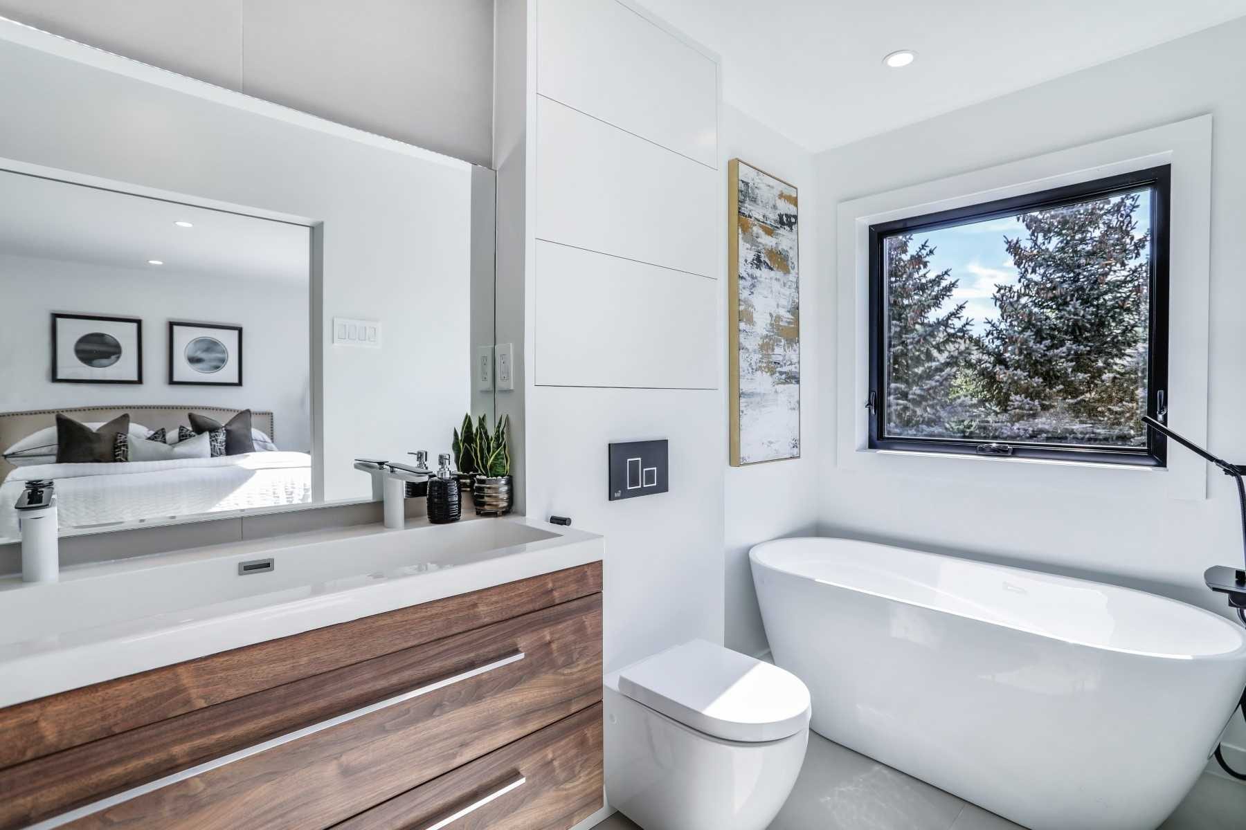 Bright bathroom with wood vanity, freestanding tub and large window
