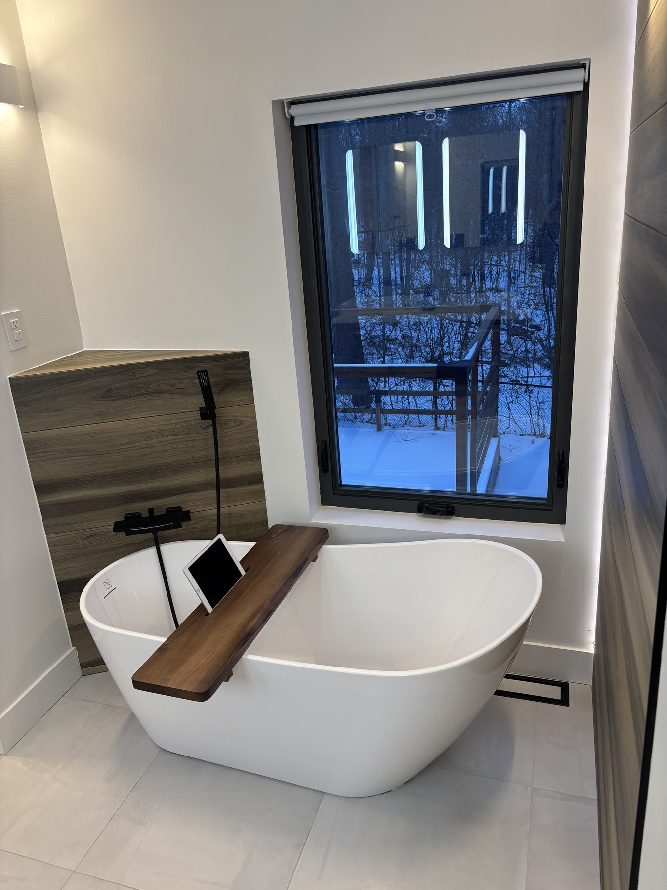 Freestanding tub set beside a black-framed window