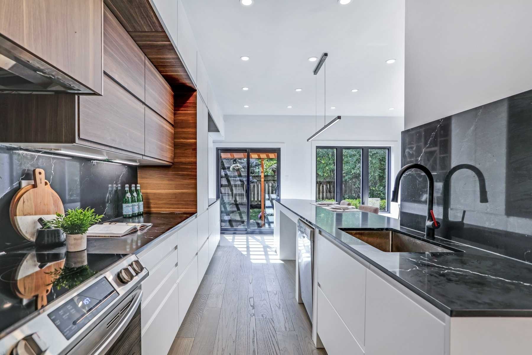 Long open kitchen with a large stone island and garden doors