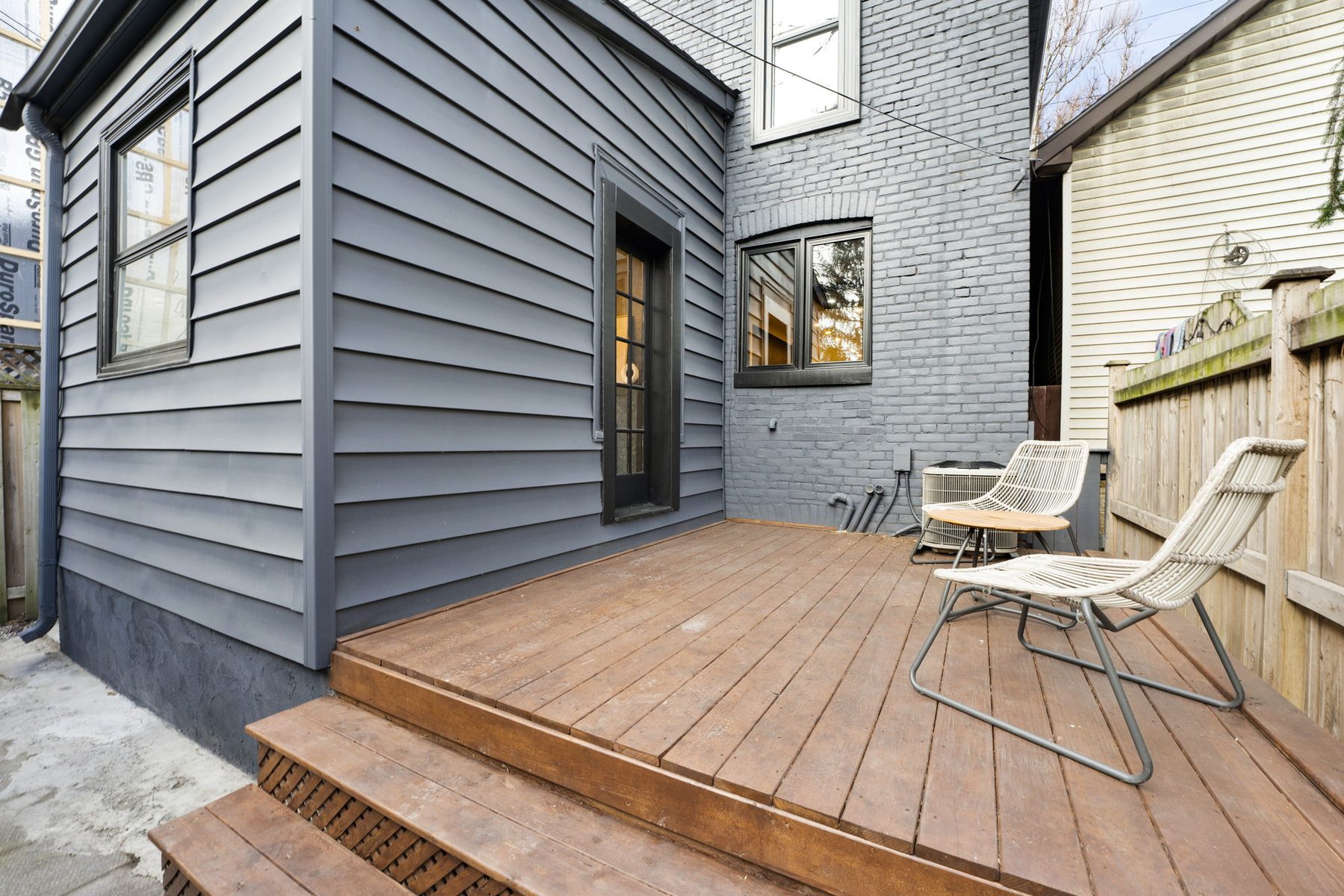 Finished rear deck with dark siding and outdoor seating