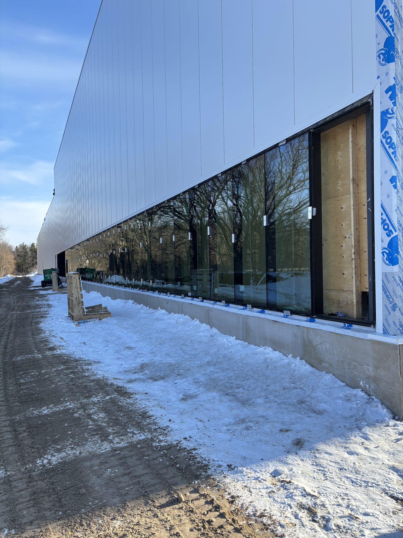 Long commercial glass façade installed beneath metal cladding